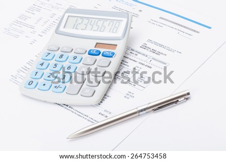 Calculator with silver pen and utility bill under it