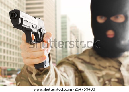 Man in black mask holding gun and city on background