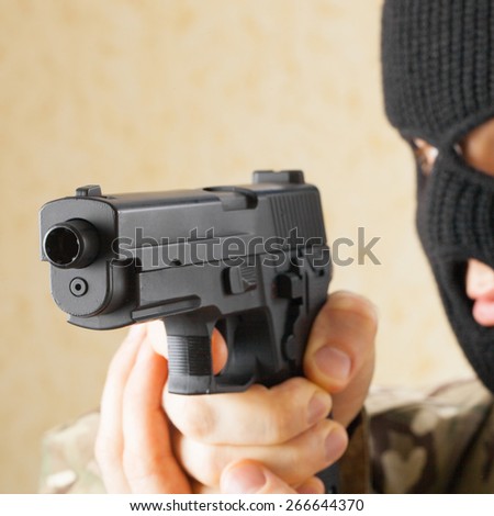 Man in mask holding gun before him - studio shot