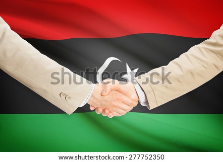 Businessmen shaking hands with flag on background - Libya