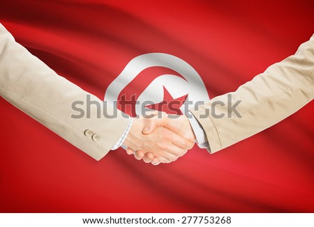Businessmen shaking hands with flag on background - Tunisia