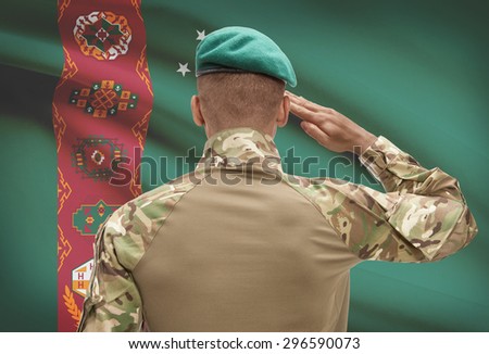 Dark-skinned soldier in hat facing national flag series - Turkmenistan