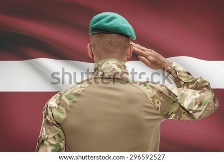 Dark-skinned soldier in hat facing national flag series - Latvia