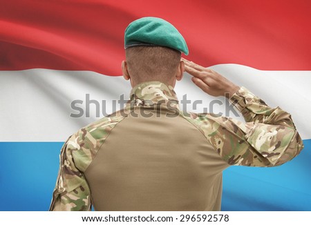 Dark-skinned soldier in hat facing national flag series - Luxembourg