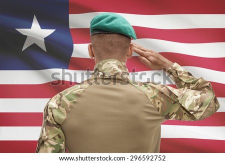 Dark-skinned soldier in hat facing national flag series - Liberia