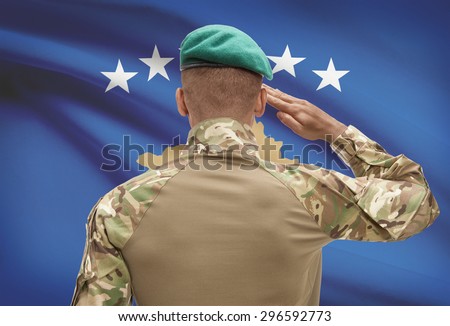 Dark-skinned soldier in hat facing national flag series - Kosovo