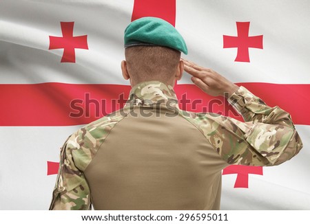 Dark-skinned soldier in hat facing national flag series - Georgia