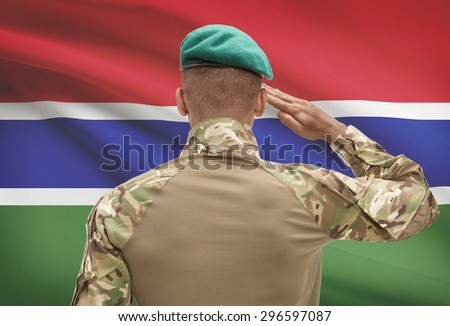 Dark-skinned soldier in hat facing national flag series - Gambia