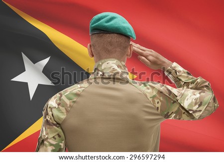 Dark-skinned soldier in hat facing national flag series - East Timor