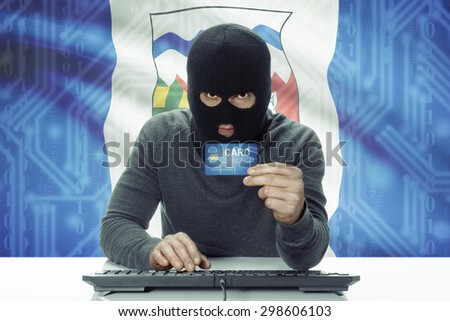 Dark-skinned hacker with credit card and Canadian province flag on background - Northwest Territories