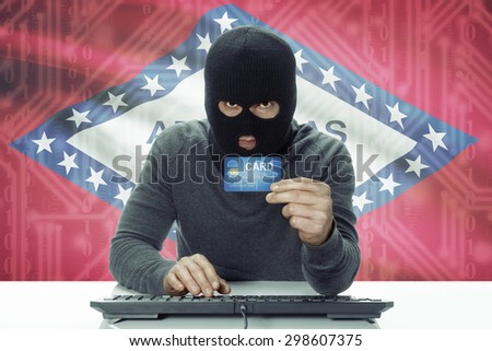 Dark-skinned hacker with credit card and USA states flag on background - Arkansas