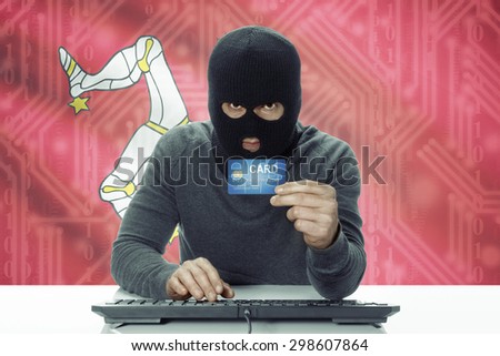 Dark-skinned hacker with credit card and flag on background - Isle of Man