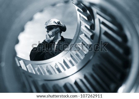 engineer seen through the shaft of a giant gear wheel, duplex blue toning concept