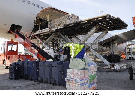airplane being loaded with cargo, luggage and bags and airport-worker