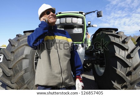 modern farmer in hardhat with large tractor