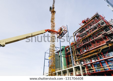 hydraulic platform hoisting site-worker in the air, factory construction plant