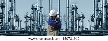 oil and gas worker pointing at large industrial refinery installation