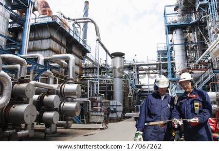 two oil and gas workers inside large refinery, oil and gas.