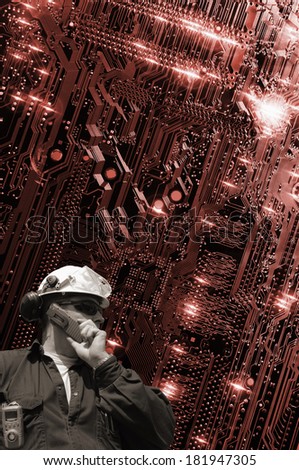 hi-tech engineer talking in phone with large circuit-board in the background