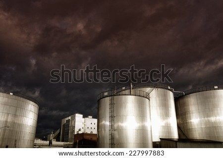 industrial oil storage tanks at sunset, sun gleaming in metal
