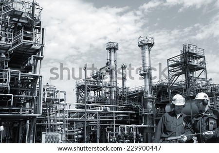 two refinery workers with large industrial refinery in background