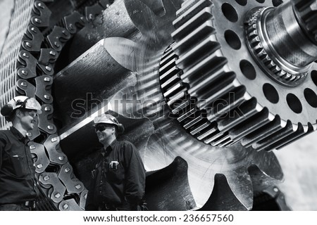 two mechanics, workers with large gears and cogs machinery
