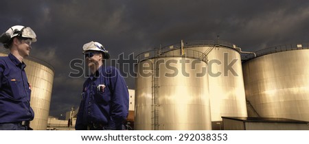 oil and fuel workers with giant storage tanks, sunset in late evening