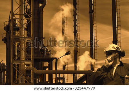 sunset over oil and gas refinery, worker in foreground