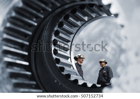 industrial workers inside giant cogwheels and gears axle, steel industry works