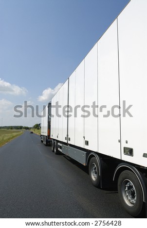 clean white truck on straight country-road, seen from ground-level and behind
