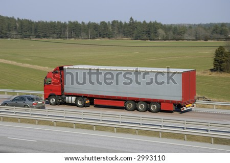 clean red truck, from the side, driving on highway with country-scenic