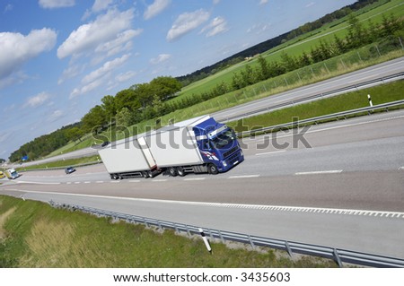 clean blue-white truck speeding on highway, no trademarks