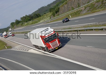 red and white truck speeding on highway, elevated frontal view