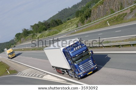 blue-white truck driving on highway surrounded by green countryside