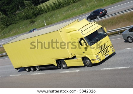 large clean yellow truck on highway surrounded by country-side