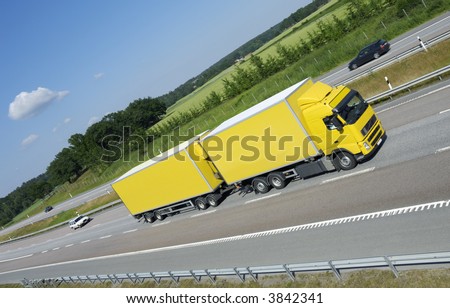 large yellow truck speeding on freeway, fields and forrest in background
