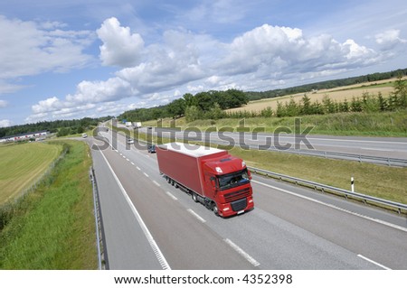 clean red truck on highway surrounded by country-side and in extreme wide-angle
