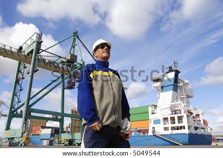 chief engineer standing in front of large commercial-port as background, crane and ship