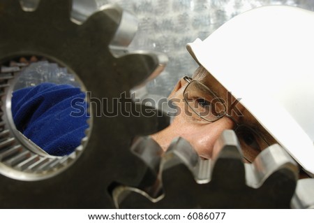 engineer in hard-hat closely examining large industrial gears