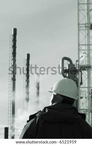 refinery with gas clouds, pipelines and pipes, with engineer in foreground, all in a greenish toning idea