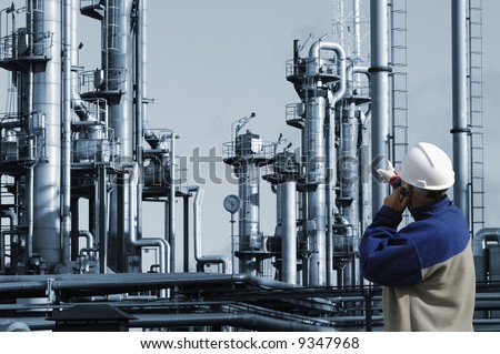 engineer in hard-hat pointing at oil and gas industrial plant