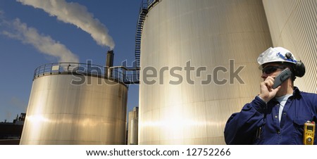 oil refinery worker with large fuel-tanks background, panorama view