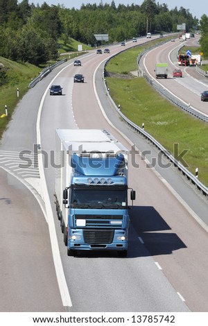 truck driving on highway surrounded by traffic, elevated shot