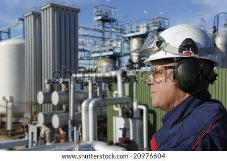 oil and gas engineer in focus, large refinery industry in background