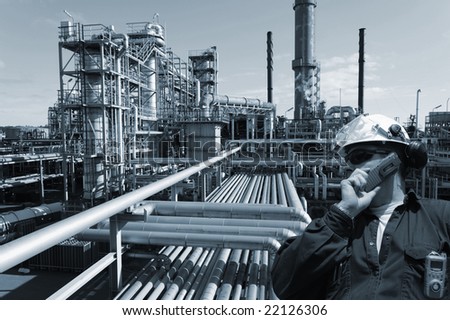 engineer talking in phone, large chemical plant, oil and gas in background, blue toning concept