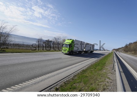 green and white truck on the move, scenic highway and sea, wide angle