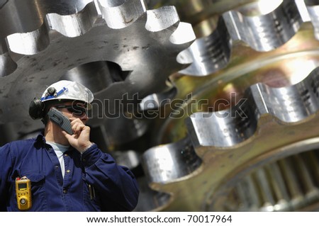 engineer, mechanic with large machine-parts in background, metal and steel industry scene