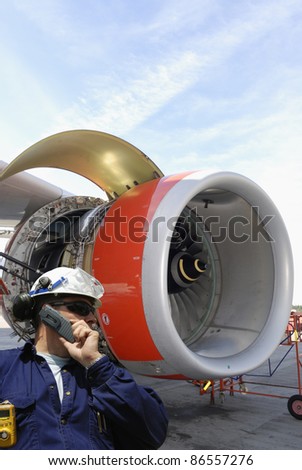 mechanic with large jet engine in background, airport maintenance works