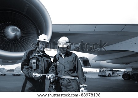 Aircraft Mechanic on Two Airplane Mechanics With Giant Jet Engine In Background  Blue