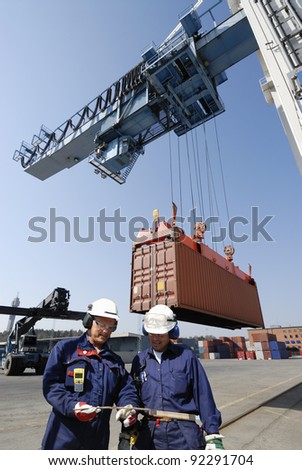 dock workers in container-port cranes and trucks inside commercial dock. dock workers in container-port cranes and trucks inside commercial dock.